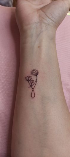 a woman's wrist with a small tattoo design on the left side of her arm