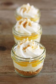 three small glass jars filled with desserts on top of a wooden table next to each other