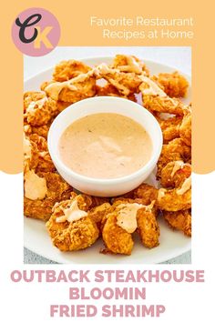 a white plate topped with fried shrimp next to a bowl of dipping sauce on top of it