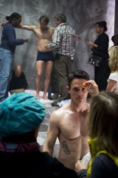 a shirtless man is standing in front of a group of people with no shirts on