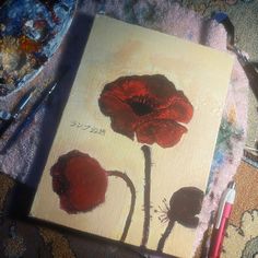 an acrylic painting of two red flowers on a piece of paper with crayons next to it