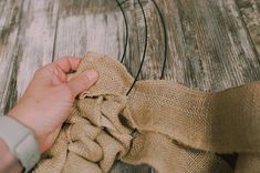 a person is tying a piece of burlock on a wooden floor with a string