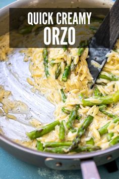 a pan filled with pasta and asparagus on top of a blue countertop