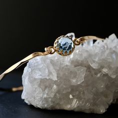 "A customizable bangle made in your choice of 14k gold fill or sterling silver featuring a gorgeous lab-created Aquamarine with incredible micro facets. The 8mm gem boasts a lovely soft blue color and a glossy, vitreous luster. The hand-forged bangle is available in two shapes and finishes. Both styles include a clasp located beside the gem for a closer fit. STYLE & SIZE options are detailed below.  METAL OPTIONS  925 Sterling Silver  14K Yellow Gold Filled (with premium plated setting)   STYLE Bangles Making, The Bangles, Sterling Bracelets, Aquamarine Jewelry, March Birthstone, Birthstone Gifts, March Birth Stone, Fit Style, Hand Forged