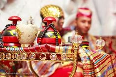 an elaborately decorated tray with red and gold items on it's sides, surrounded by other people