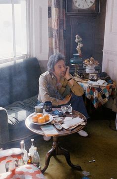 a woman sitting on a couch in front of a table filled with food and drinks