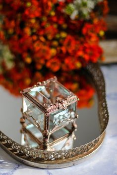 a glass box sitting on top of a table next to a vase filled with flowers