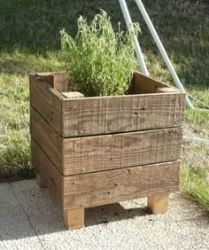 a wooden planter sitting on top of a sidewalk next to a grass covered field