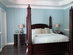 a bedroom with blue walls and white bedding in the center, along with two nightstands on either side of the bed