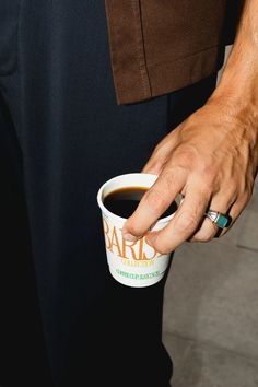 a close up of a person holding a cup of coffee with their hand on it