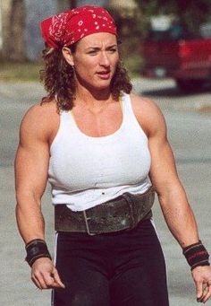 a woman riding a skateboard down a street while wearing a bandana on her head