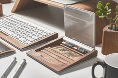 a desk with a keyboard, mouse pad and pen holder on it next to a laptop