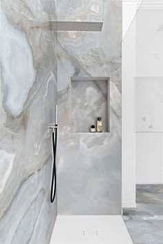 a bathroom with marble walls and flooring, including a shower head in the corner