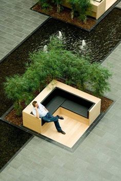 a man sitting on top of a bench next to a pond