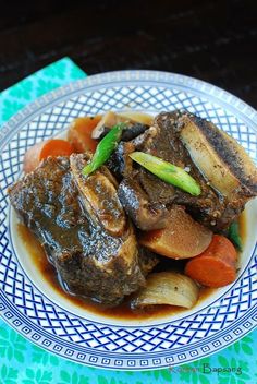 a white and blue plate topped with meat and vegetables