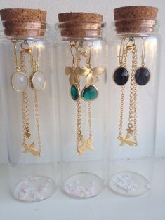 three glass jars filled with different types of necklaces