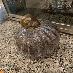 a silver pumpkin sitting on top of a counter next to a glass case with a door in the background