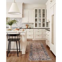 a kitchen with white cabinets and an area rug on the floor in front of it