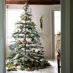 a decorated christmas tree in the corner of a room with white walls and flooring