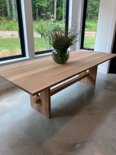 a wooden table sitting in front of two large windows