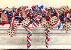 red, white and blue patriotic bow with stars on it hanging from the mantle in front of a fireplace