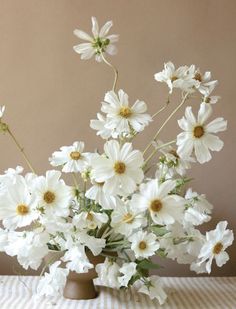 a vase filled with lots of white flowers on top of a checkered table cloth