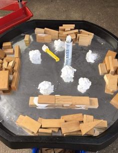 a black tray filled with blocks of wood and foam on top of a cement floor