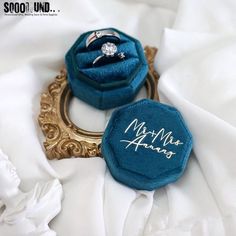 two wedding rings sitting on top of a blue ring box with the word mr and mrs written on it