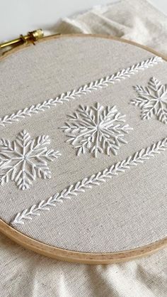 an embroidered snowflake pattern on a white linen with gold thread in the hoop