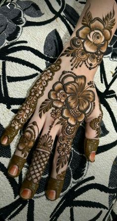 a woman's hand with hennap and flowers painted on it, showing the intricate