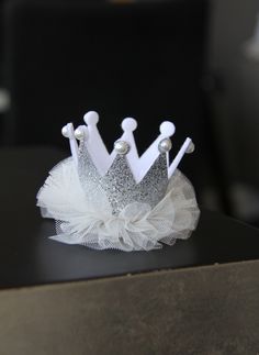 a tiara sitting on top of a table in front of a black chair with white tulle