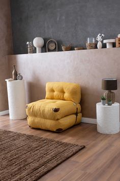 a yellow chair sitting on top of a hard wood floor next to a white vase