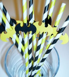 black and yellow striped paper drinking straws in a glass bowl with batman cutouts