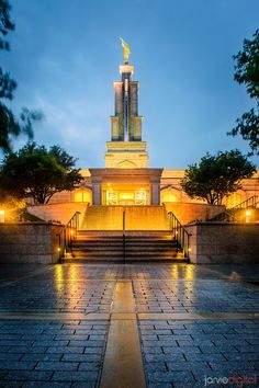 the building is lit up at night with its lights on and steps leading to it