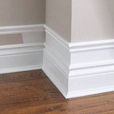 the corner of a room with white walls and wood flooring is shown in this image