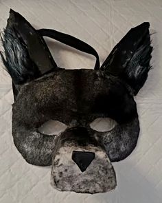 an animal mask is shown on a white sheet with black fur and ears, as if it were made out of paper