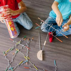 two children sitting on the floor playing with sticks and magnets in front of them