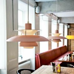 three lamps hanging from the ceiling over a table in a room with red booths and chairs