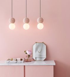 a pink room with three lights hanging from the ceiling and a mirror on the wall