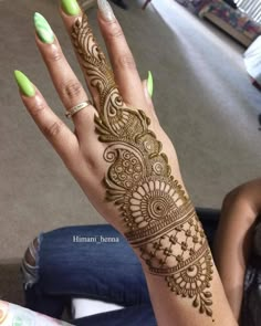 a woman's hand with henna on it and green nails in the foreground