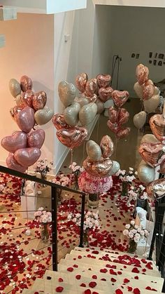 balloons and confetti are on the floor in front of a staircase that is decorated with rose petals