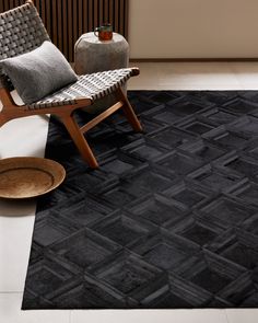 a black and white area rug with a chair in the corner next to it on top of a hard wood floor