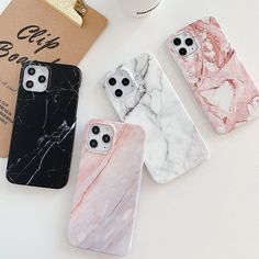 three marble iphone cases sitting on top of a table next to a coffee cup and book