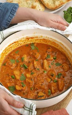 two hands holding a bowl of chicken curry