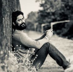 a man sitting on the ground next to a tree