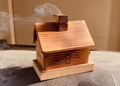 a small wooden house sitting on top of a table next to a smokestack