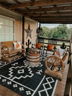 an outdoor porch with rocking chairs and rugs on the wooden flooring, along with two wagon wheels