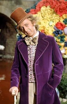 an old man in a purple coat and top hat holding a cane while standing next to a flower arrangement