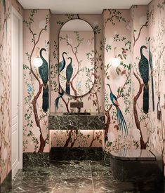 a bathroom decorated in pink and green with peacocks on the wall, mirror above it