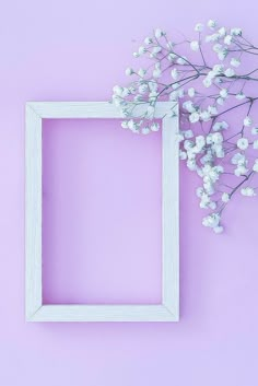 a white frame sitting on top of a purple wall next to a flower vase with baby's breath